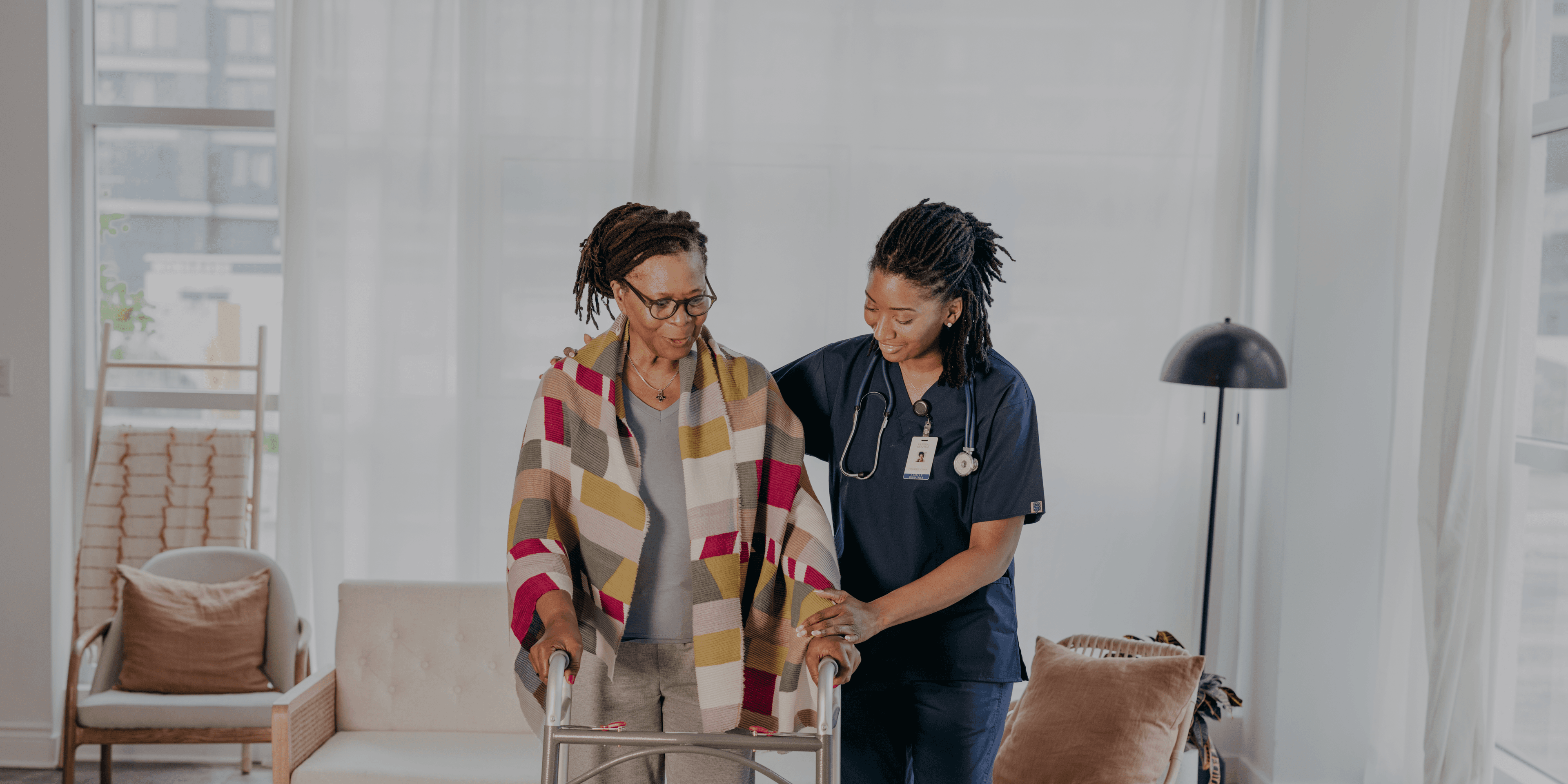 Zorgmedewerker helpt vrouw met rollator lopen