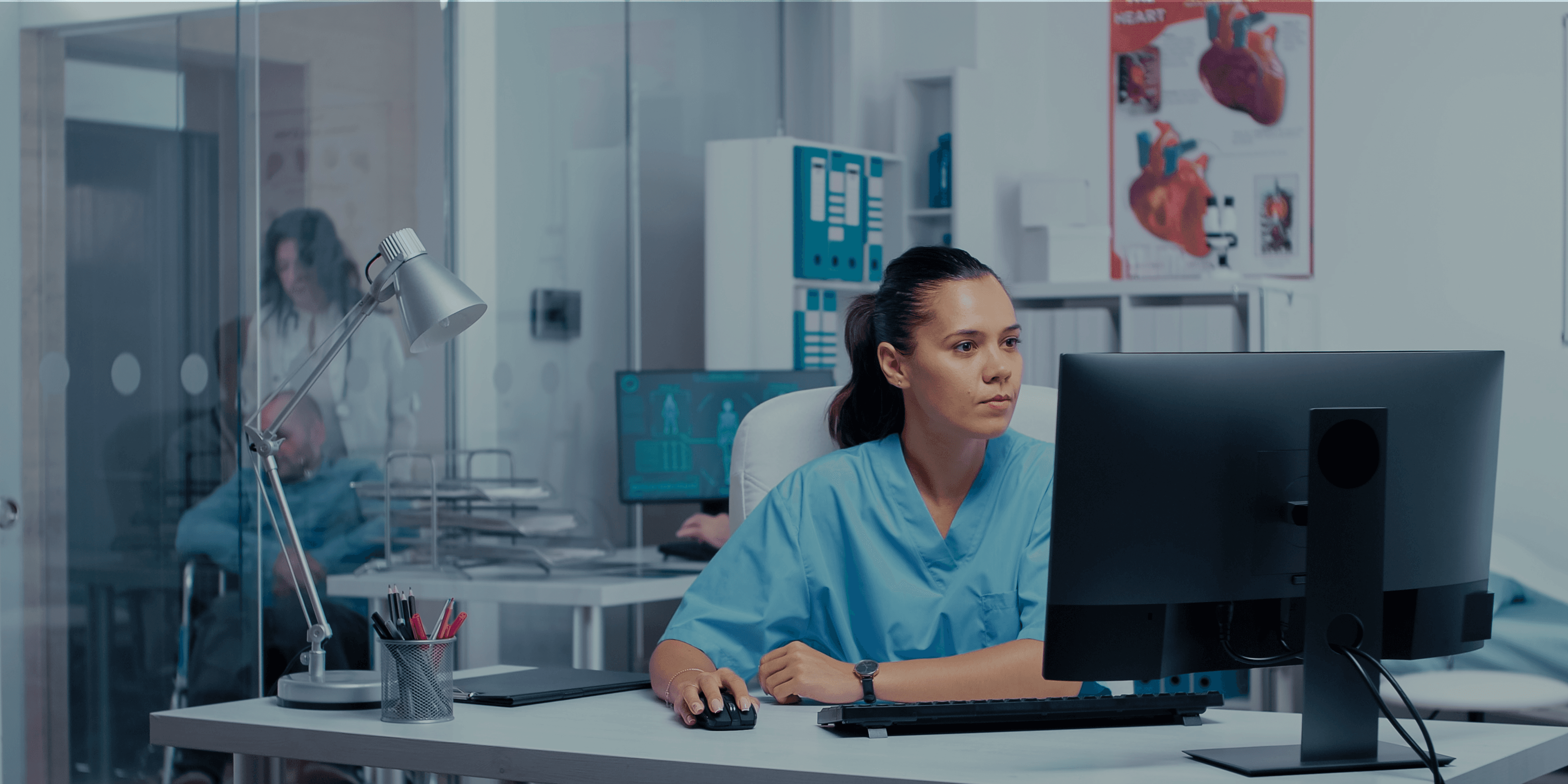 Zorgmedewerker achter haar computer in een behandelruimte